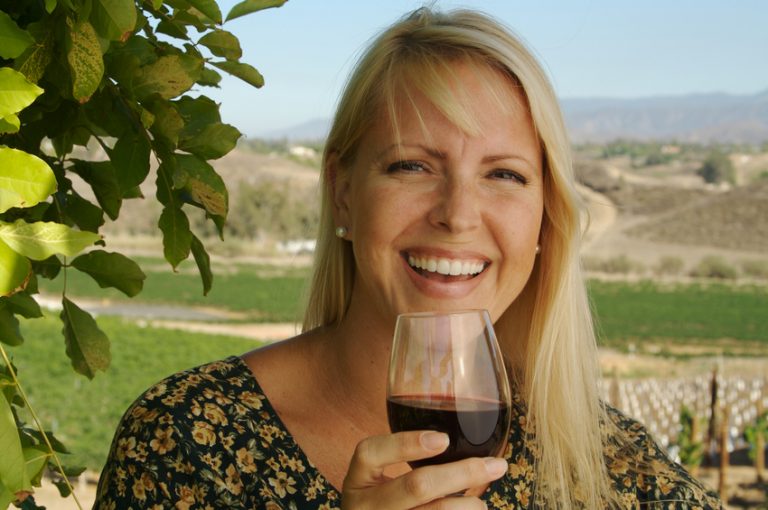 Beautiful woman smiling as she is wine tasting on a summer day.